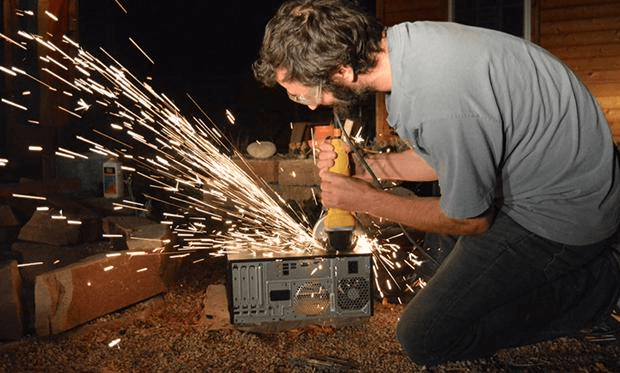 Photo showing a man opening the back of a computer case using a grinder